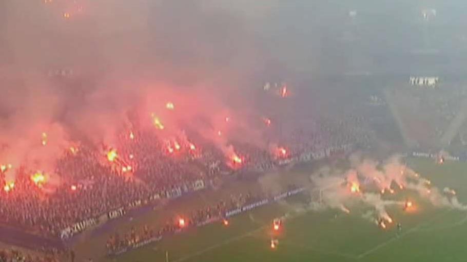 Opposing soccer fans light fireworks, throw flares on field