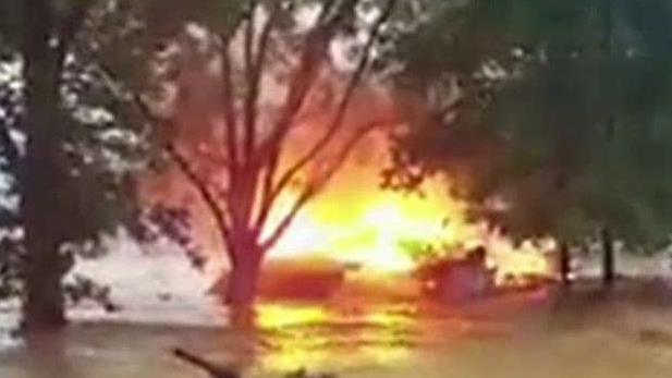 Burning house uprooted by West Virginia floodwaters