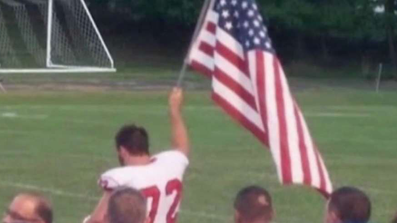 High school football player raises American flag at game
