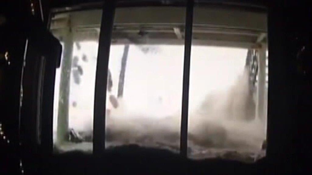 Storm surge waves crash against oceanfront home's windows