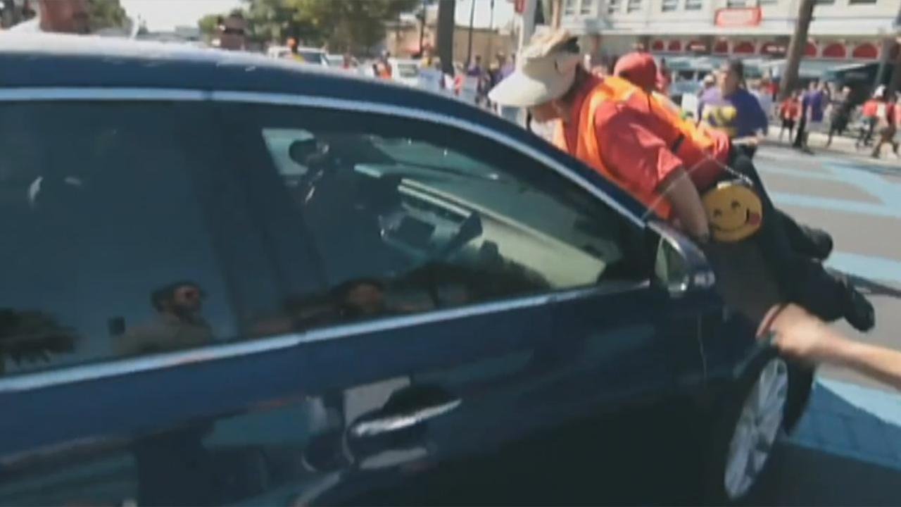Car drives through group of immigration protesters