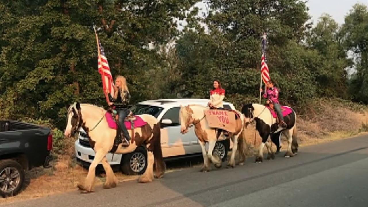 Girls carry flags on horseback to thank first responders