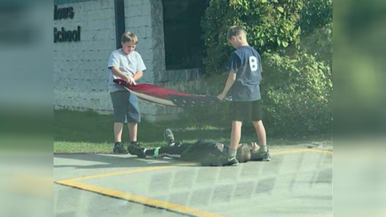 Boy lays down to keep flag from hitting the ground