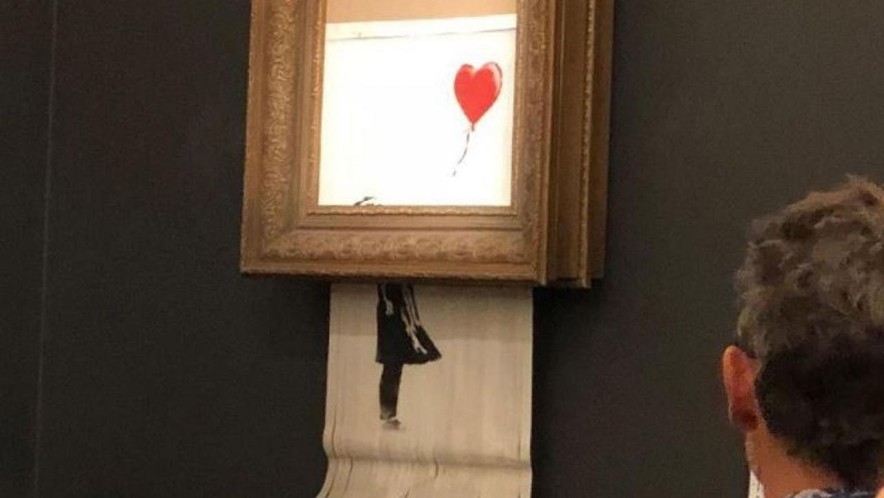 A Banksy stencil spray painting triples its auction estimate and becomes a record for the elusive artists. However, seconds after it was officially sold, the piece runs through a shredder hidden in the frame.