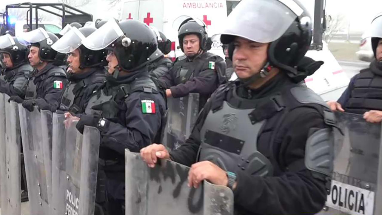 Mexican police in riot gear line up at US border as migrant caravan arrives