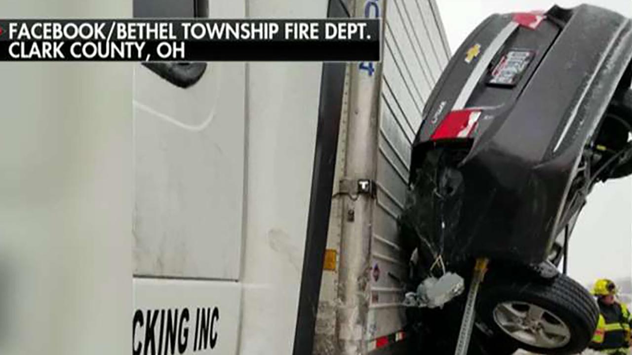 Car pinned between highway barrier and semi-truck