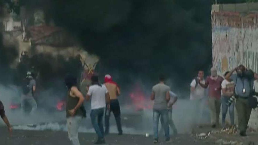 Venezuelan citizens attempt to remove barricades that are blocking aid from entering the country