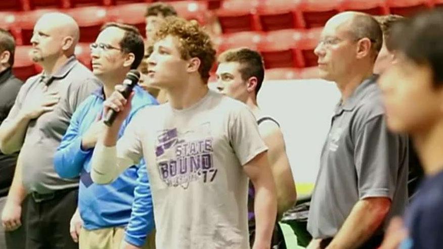 High school wrestler steps up to sing national anthem at tournament