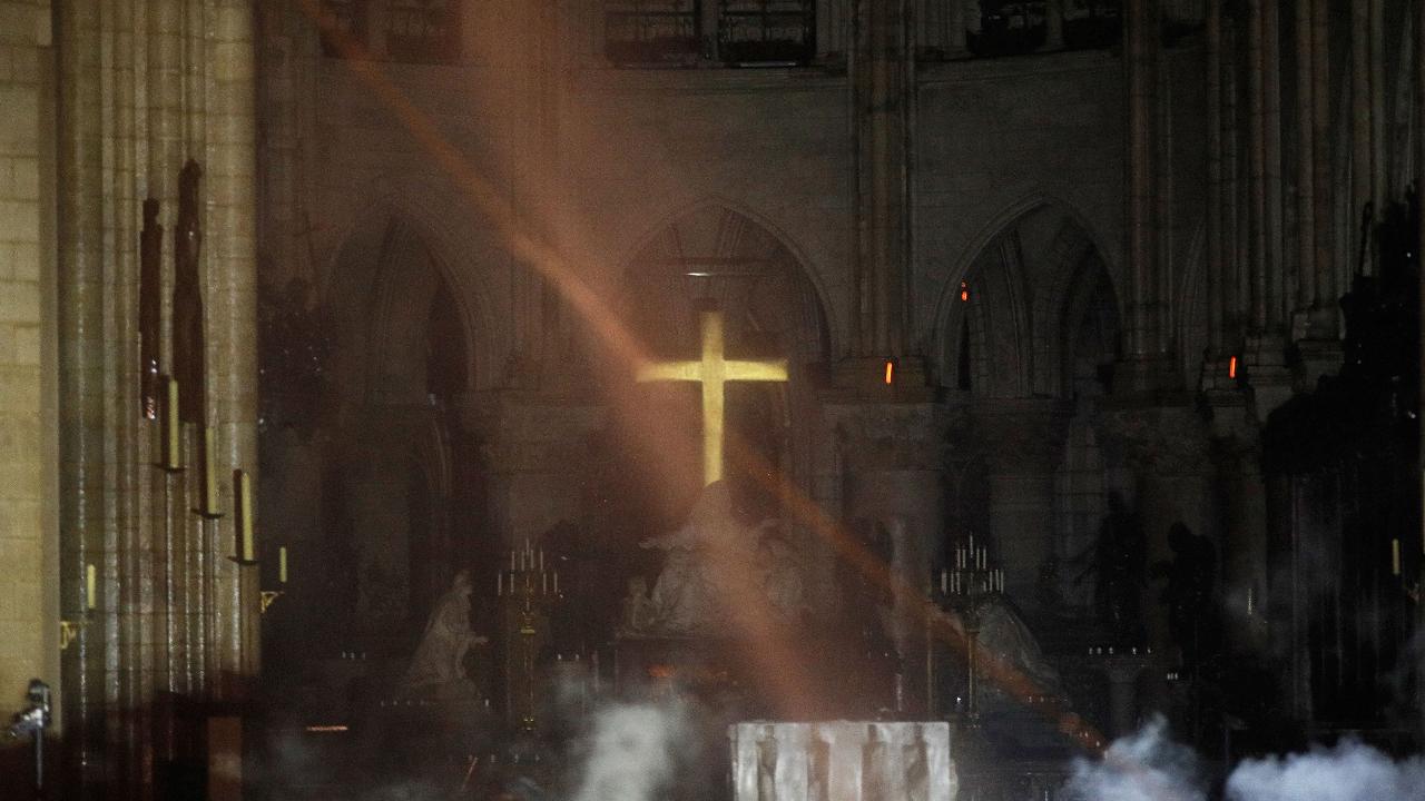 Notre Dame’s golden altar cross seen glowing among the ashes as images emerge from inside show fire-ravaged cathedral