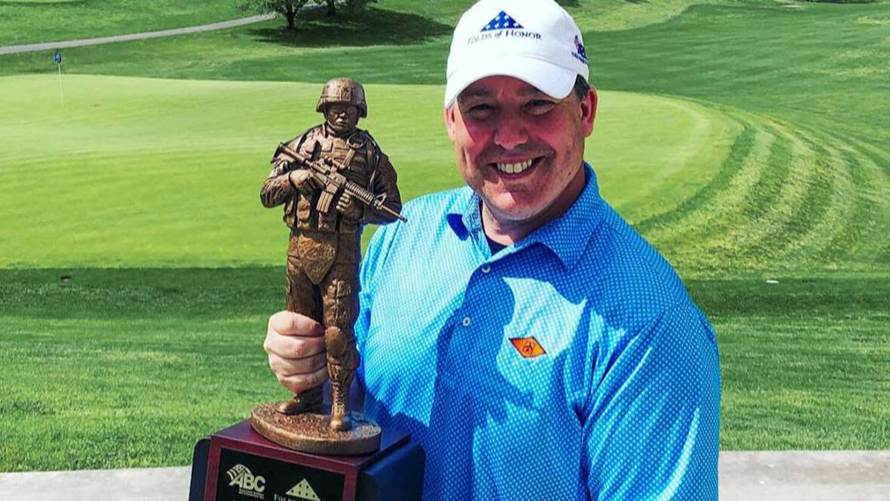 Ed Henry receives the Folds of Honor trophy during a charity golf tournament