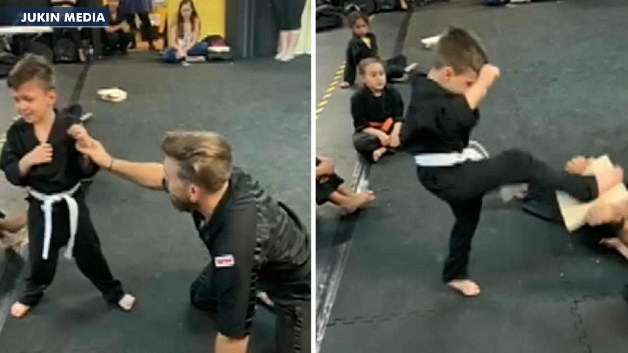 Karate class cheers on student having trouble breaking board
